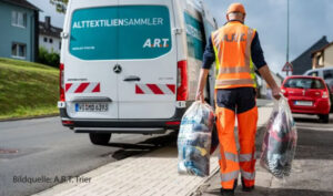 Ein Mitarbeiter der A.R.T. trägt Alttextilsäcke ins Auto